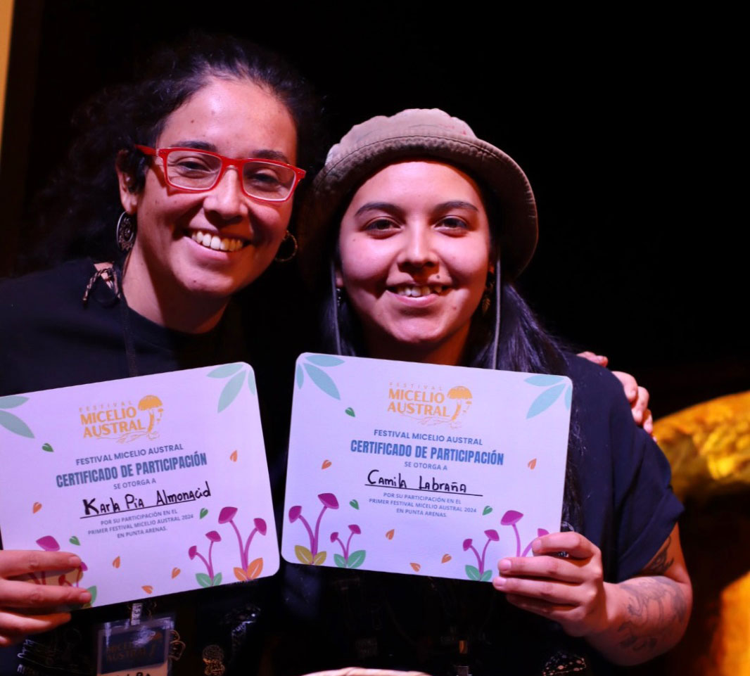 Dos compañeras del equipo de Simbiosis Subantártica en la Patagonia chilena recibiendo diplomas de participación en el Festival Micelio Austral